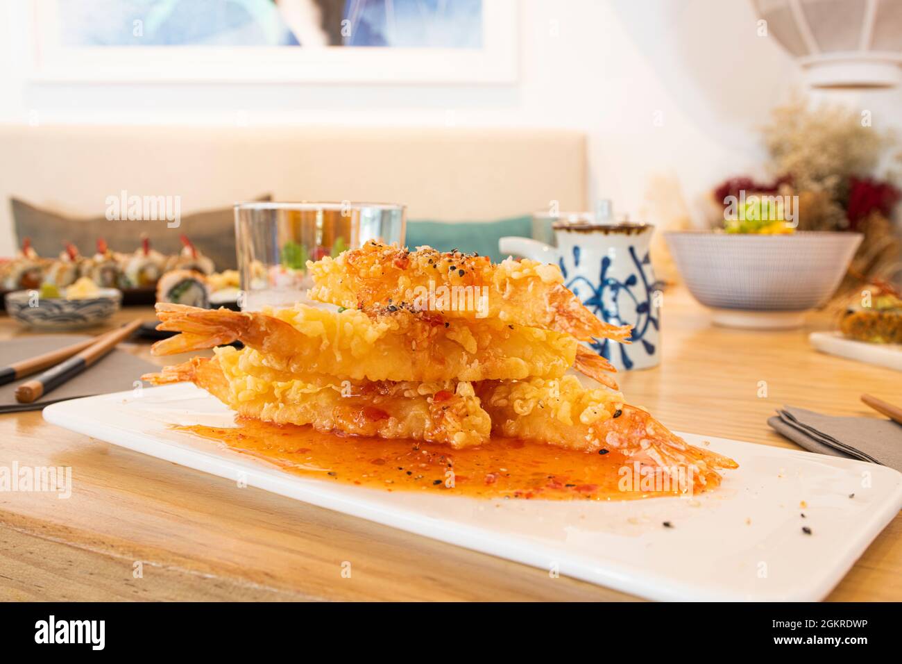 In einem japanischen Restaurant mit hellen Holztischen werden gebratene Garnelen aus Panko-Mehl serviert Stockfoto