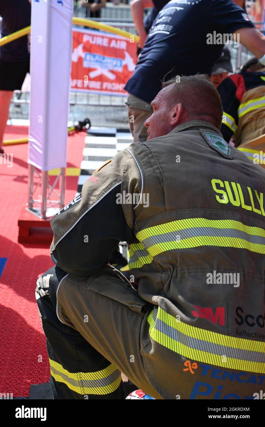 Master-Sgt. Sean Sullivan, Assistant Chief of Training in der 445. Civil Engineer Squadron, erholt sich knieend und blickt auf die offizielle Zeituhr nach seiner letzten Wettbewerbsrunde bei den FireFit Europe Championships am 20. Juni 2021. Die Veranstalter haben den Hindernisparcours in Hannover für die diesjährigen Meisterschaften zusammengestellt. Sullivans letzte Kurslaufzeit betrug 1:29.46, was ihm den ersten Platz in der Altersgruppe über 40 und den achten Platz in der Gesamtwertung einbrachte. Stockfoto