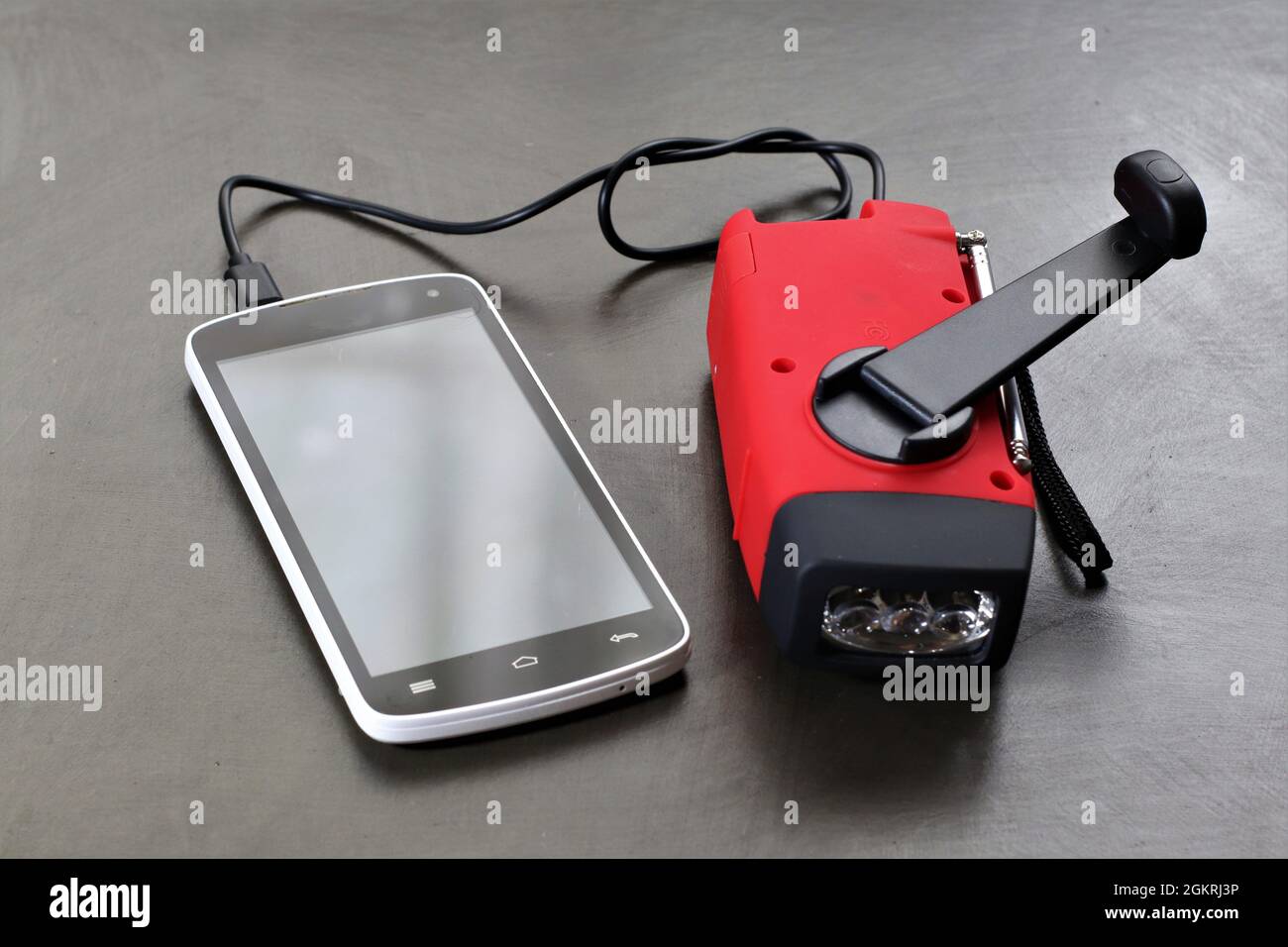 Wenn Sie sich in einer Notsituation befinden und keine Steckdose zum Aufladen Ihres Mobiltelefons haben, kann dieses Handkurbel-Ladegerät ein Lebensretter sein. Stockfoto
