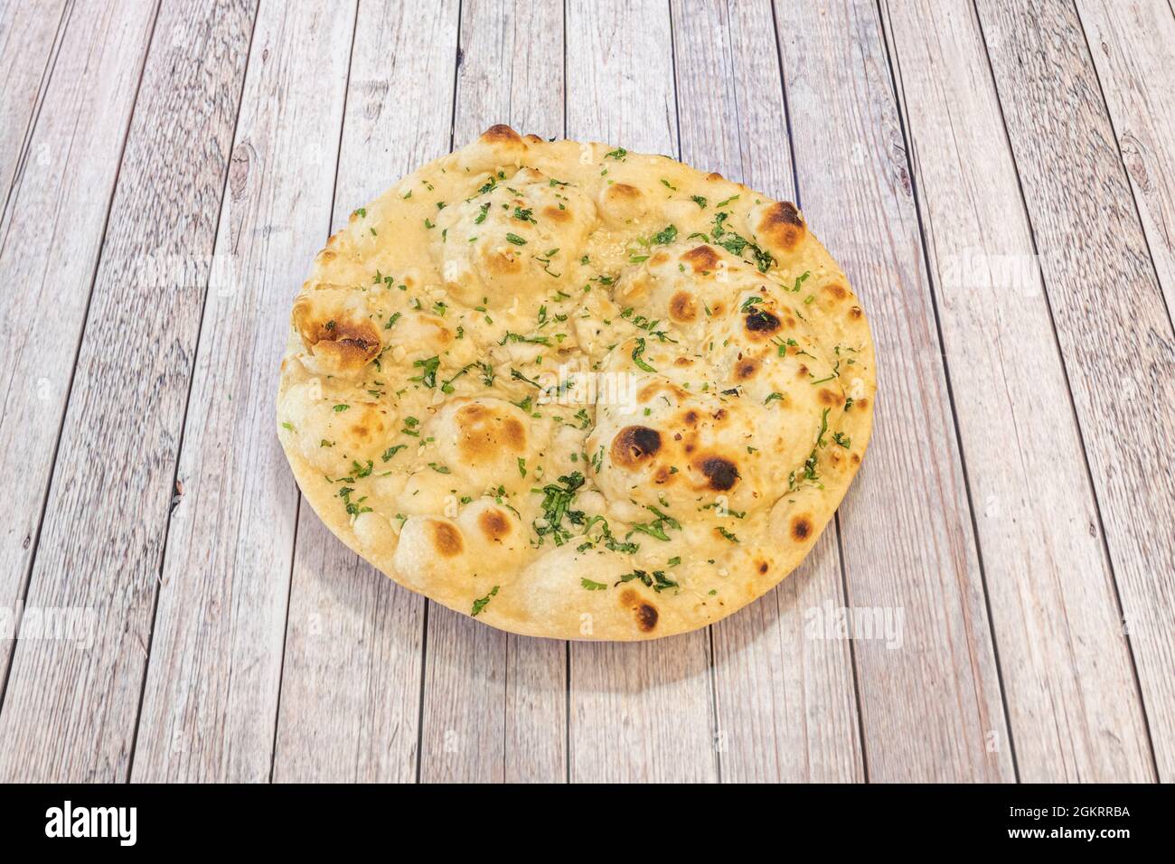 Knoblauchbrot-Wafer mit naanindischem Rezept, zubereitet im pakistanischen Restaurant mit viel Petersilie und Knoblauch auf dem hellen Tisch Stockfoto