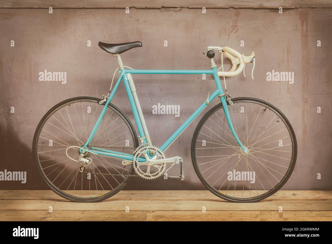 Vintage siebziger Jahre hellblaues Rennrad auf einem Holzboden mit einer verwitterten Hintergrundwand Stockfoto
