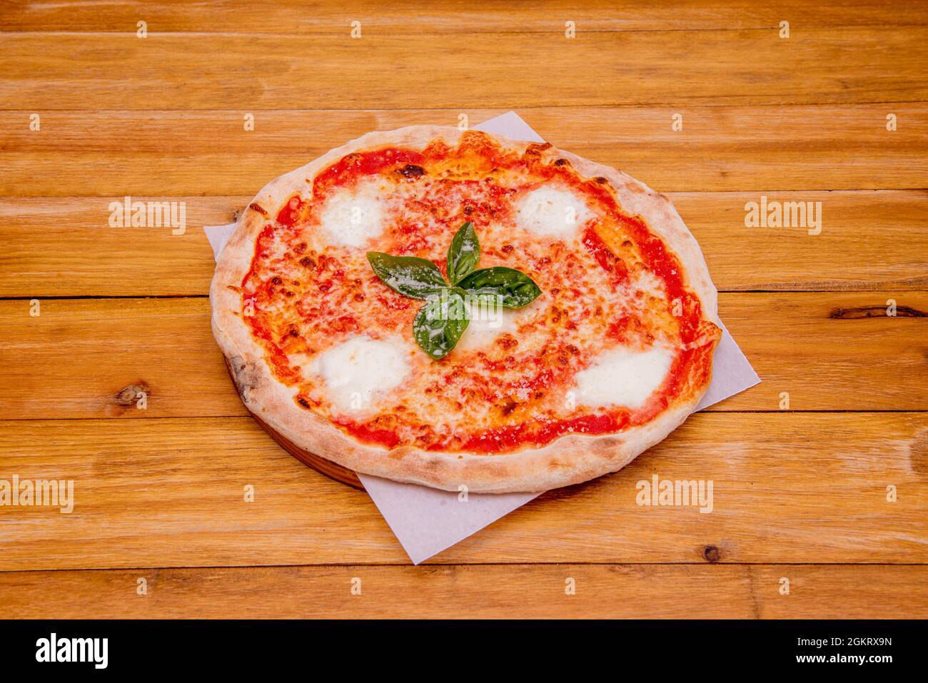 Kleine margarita Pizza mit geschmolzenen Büffelkäsebällchen, Tomaten und Mozzarella-Käse auf weißem, fettfestem Papier Stockfoto