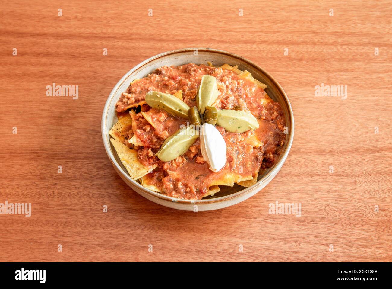 Schüssel Mais Nachos in würzigen Chili con Carne mit Guacamole und Frischkäse getränkt Stockfoto