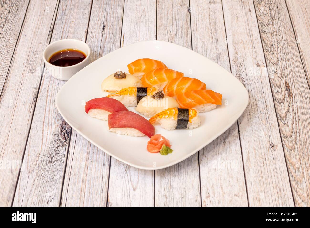 Teller mit gemischtem Lachs-Nigiri-Sushi, Garnelen auf Reis, rotem Thunfisch, Butterfisch mit Fischrogen mit Wasabi und Ginseng mit Schüssel mit Sojasauce Stockfoto