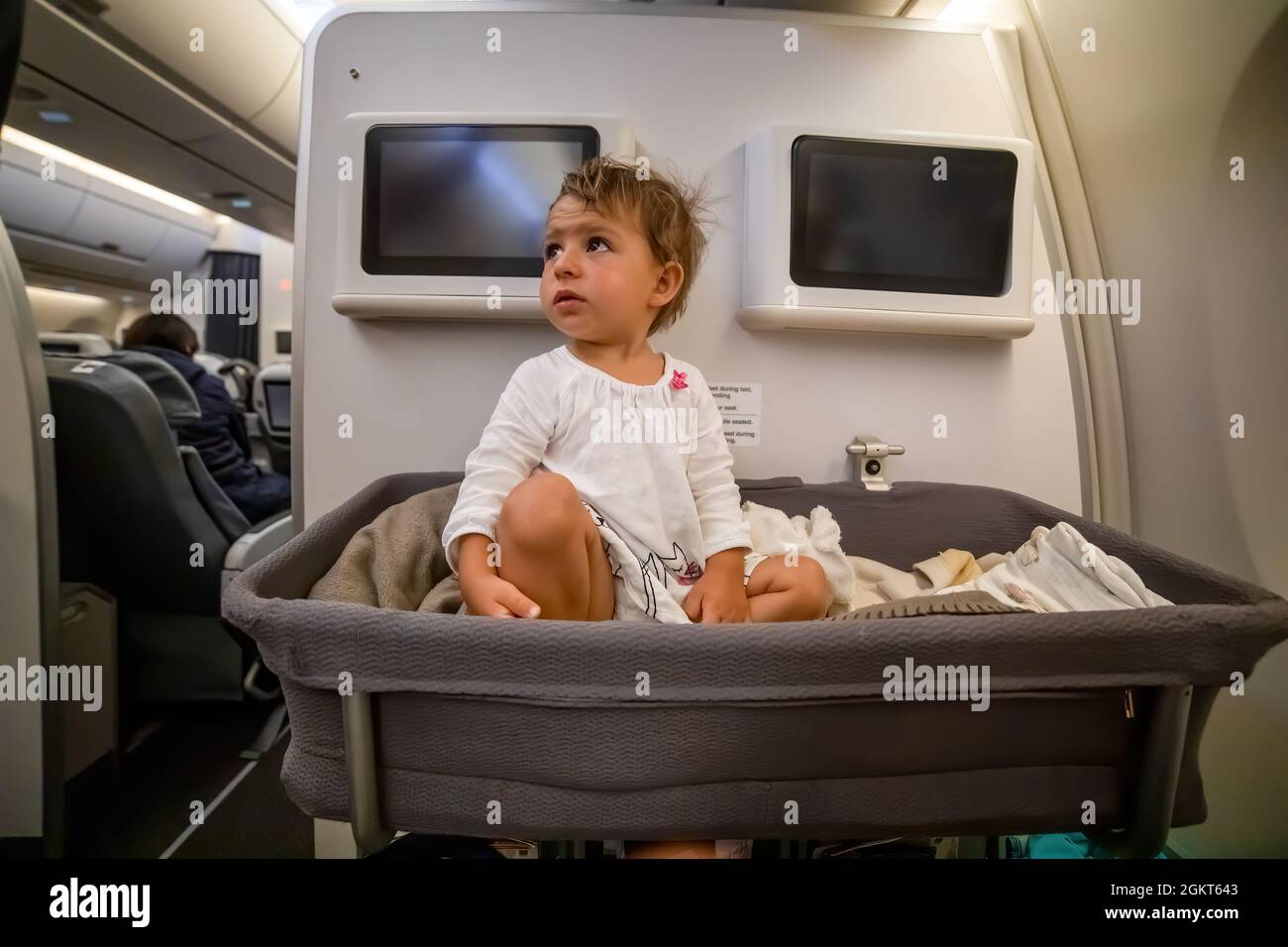 Baby Boy aufwachen über dem Schlafen in Bassinet im Flugzeug. Kleinkind Passagier an Bord. Erster Flug Stockfoto