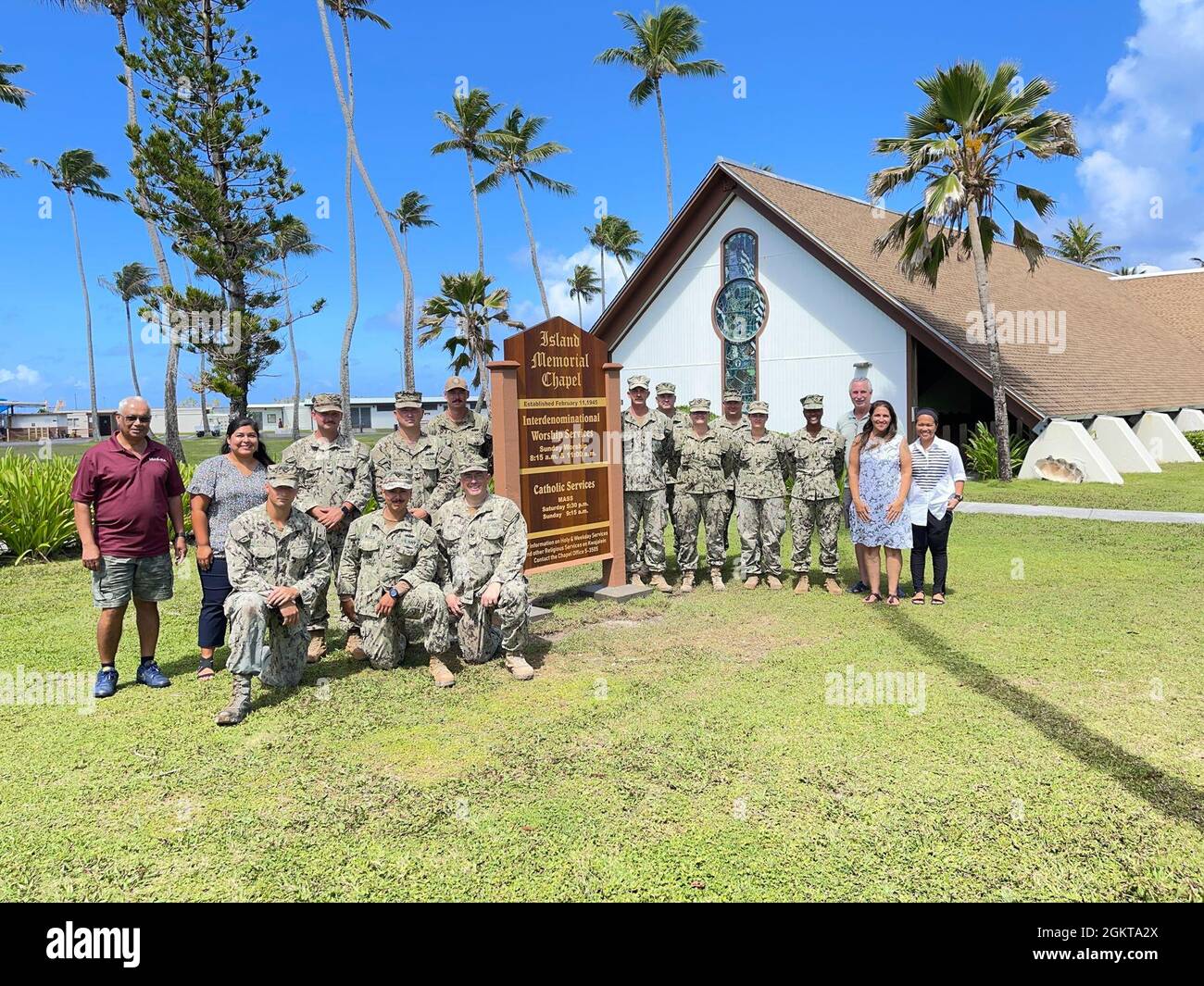 Mitarbeiter der historischen Island Memorial Chapel und des U.S. Naval Mobile Construction Bataillon 4, Detail Marshall Islands, posieren für ein maskenfreies Foto vor einem neuen Kapelleplakat auf dem US Army Garrison-Kwajalein Atoll am 26. Juni 2021. NMCB-4-Bauexperten spielten eine Schlüsselrolle bei der Fertigstellung der Installation, nachdem sich das Projekt durch die Pandemie verzögert hatte. USAG-KA hat keine bekannten aktiven Fälle von Covid-19. Die strikte Durchsetzung von Quarantäneprotokollen ermöglicht es Bewohnern und Mitarbeitern, weitgehend maskenfrei zu arbeiten. Stockfoto