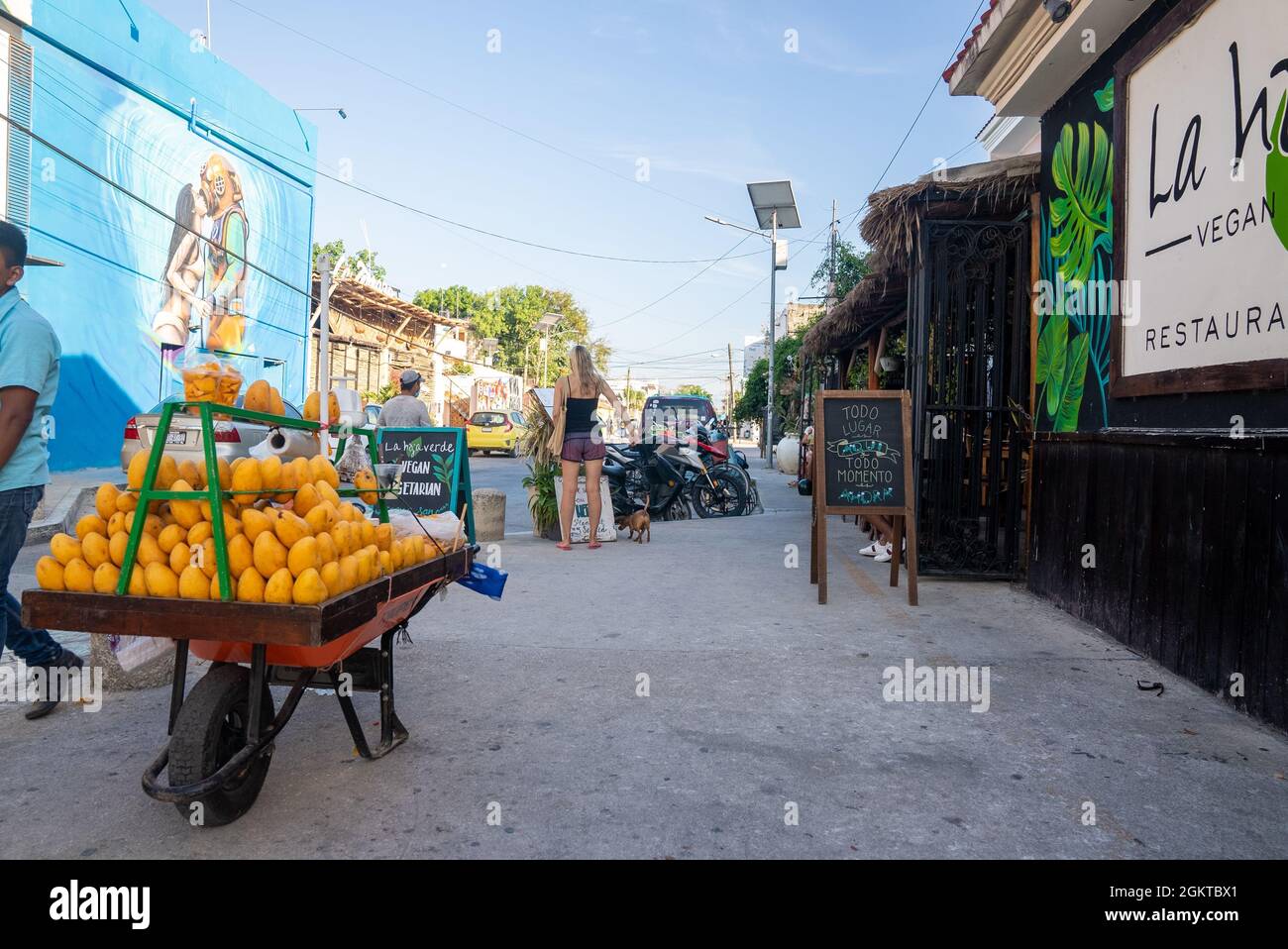 Mango-Obstwagen mit Fußgängern im Restaurant am Straßenrand mit Schildern Stockfoto