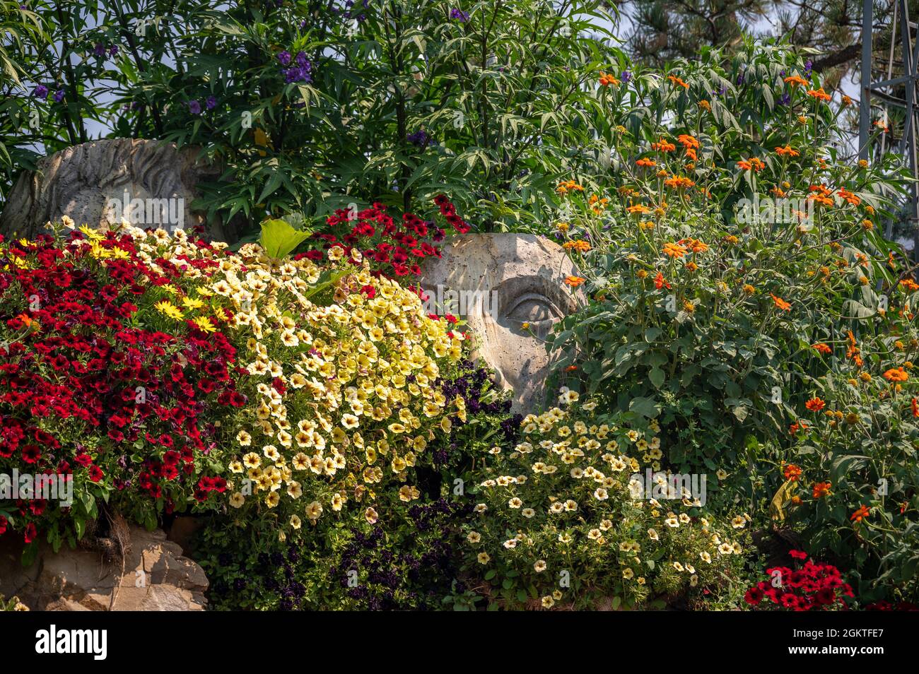 Horizont Ansicht von zwei großen Statuen in einem Garten hat mit mehreren Arten von schönen Blumen bedeckt Stockfoto