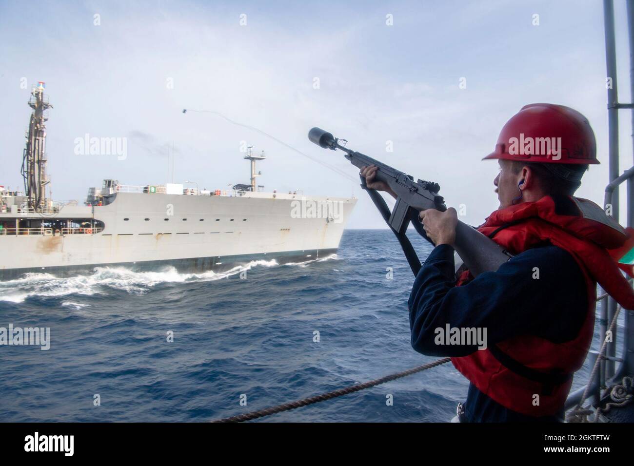 210629-N-JW440-2027 ARABIAN SEA (29. Juni 2021) - Gunners Mate 3rd Class Jonathan Winfield feuert eine Schusslinie vom Lenkraketen-Kreuzer USS Shiloh (CG-67) zum militärischen Sealift Command Fleet Replenishment Oiler USNS Pecos (T-AO 197) während einer Wiederauffüllung auf See im Arabischen Meer, 29. Juni. Shiloh wird in den Einsatzbereich der 5. US-Flotte eingesetzt, um Marineinteraktionen zu unterstützen, um die maritime Stabilität und Sicherheit in der Zentralregion zu gewährleisten und das Mittelmeer und den Pazifik durch den westlichen Indischen Ozean und drei strategische Engpässe zu verbinden. Stockfoto