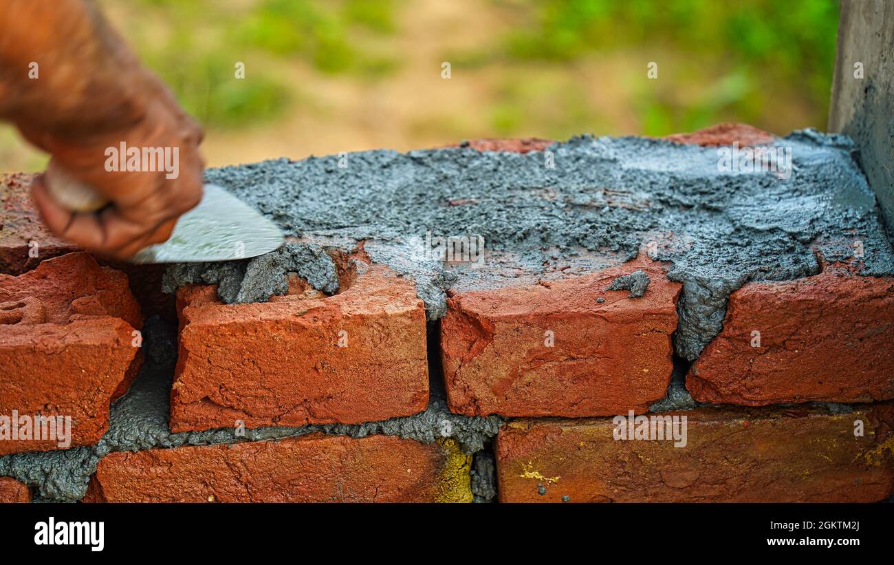 Maurer Arbeiter Installation von Mauerwerk an der Außenwand mit Kelle Kitt Messer lokalen Grafschaft in Indien. Stockfoto