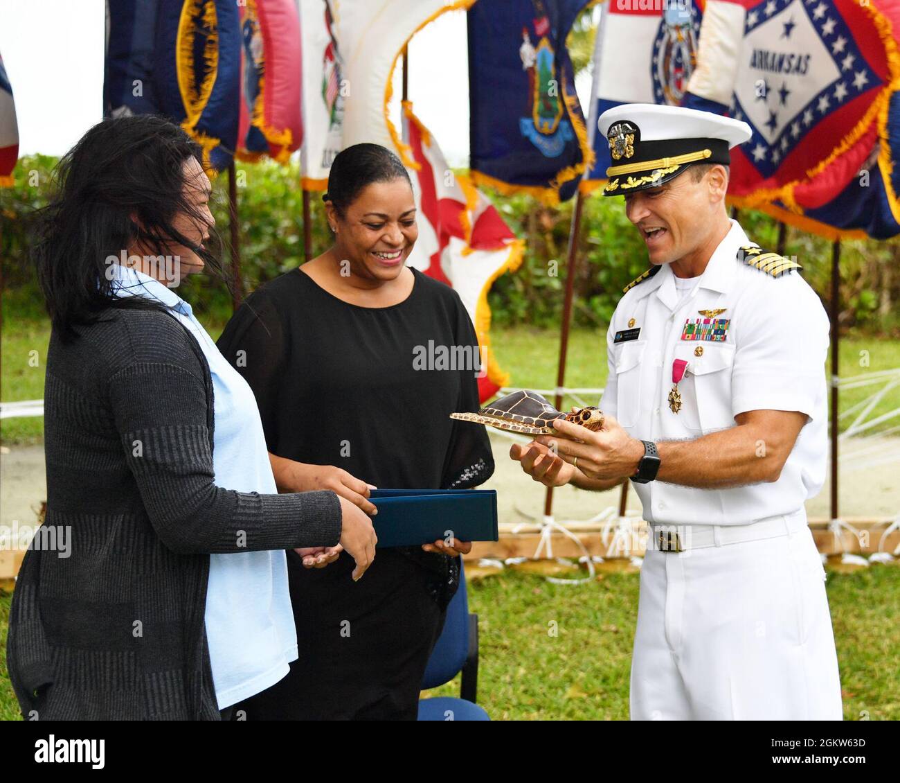 DIEGO GARCIA, Britisches Territorium im Indischen Ozean (6. Juli 2021) – Frau Yam und Frau Faviola, Vertreter des Filmau Club auf Diego Garcia, präsentieren Capt. R Wade Blizzard, den Kommandanten der US-Navy Support Facility, Diego Garcia, Mit einem Zertifikat und einer geschnitzten Holzschildkröte während einer Befehlswechselzeremonie am 6. Juli 2021. NSF Diego Garcia bietet Logistik-, Service-, Freizeit- und administrative Unterstützung für US- und alliierte Truppen, die im Indischen Ozean und im Arabischen Golf eingesetzt werden. Stockfoto