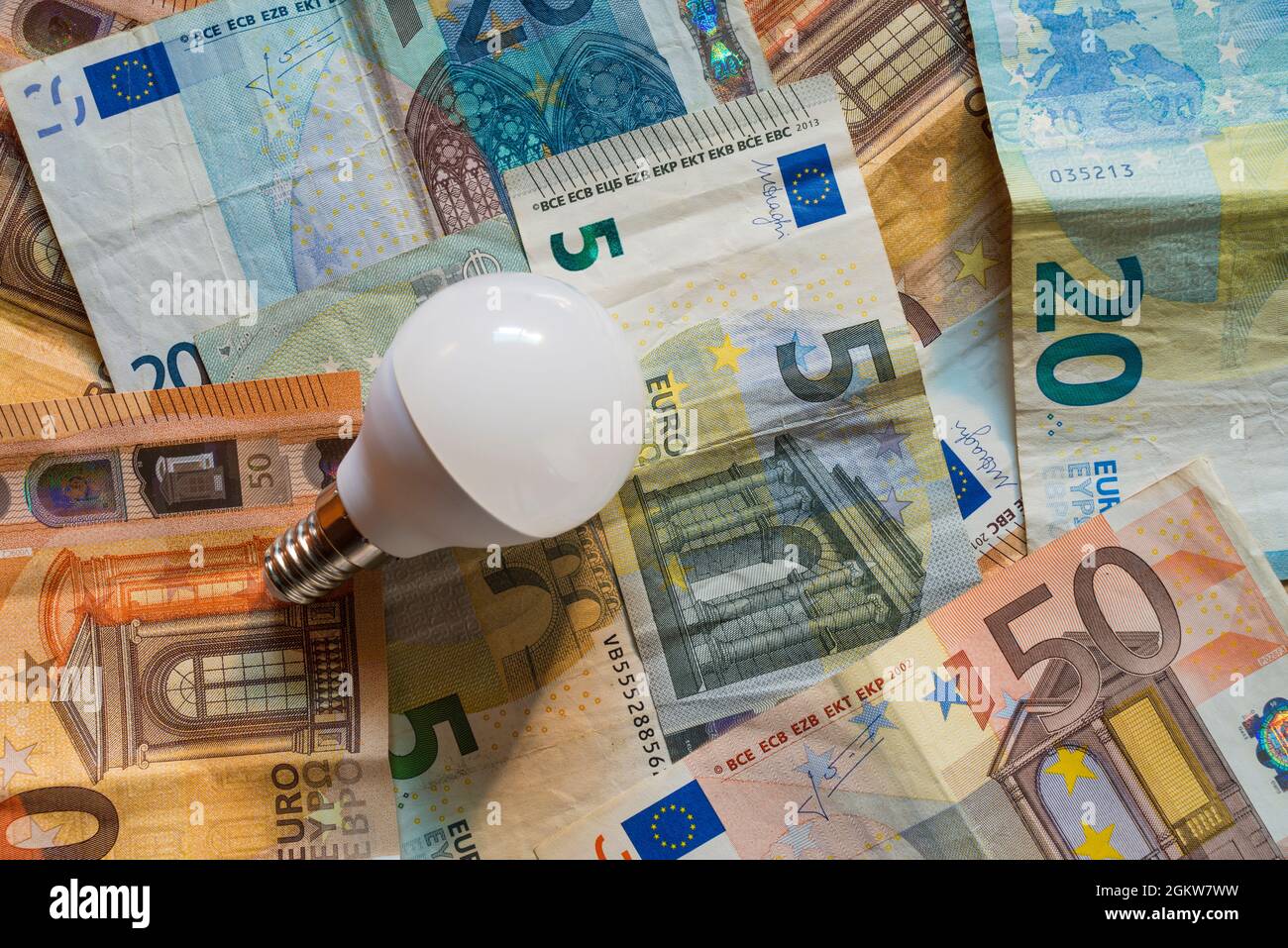 Glühbirne auf einem Hintergrund von Euro-Banknoten. Konzept der steigenden Strompreise. Stockfoto