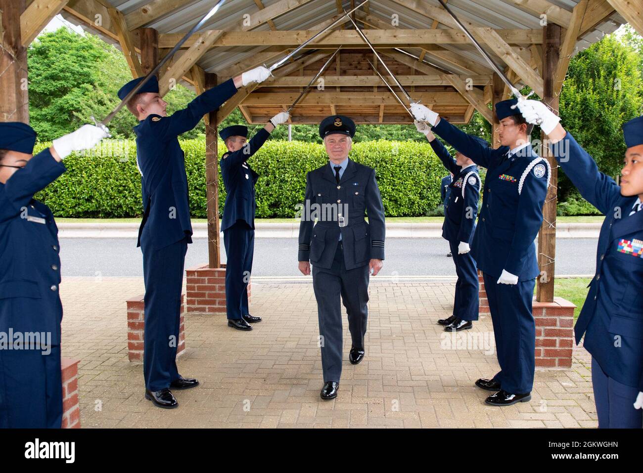 Royal Air Force Squn. Ldr. Clive Wood, Zentrum, RAF Alconbury und RAF Molesworth RAF Commander, spaziert durch einen Säbelbogen, der von Air Force Junior ROTC Kadetten während des Jahresempfangs 2021 Wing Commander bei der Royal Air Force Alconbury, England, am 9. Juli 2021 gehalten wurde. Die führenden Vertreter aus den Bezirken Cambridgeshire, East Northamptonshire und Fenland besuchten die 423. Air Base Group, wo sie die Gelegenheit hatten, Beziehungen zu ihren US-Partnern aufzubauen und mehr über die 501. Combat Support Wing Mission zu erfahren. Stockfoto