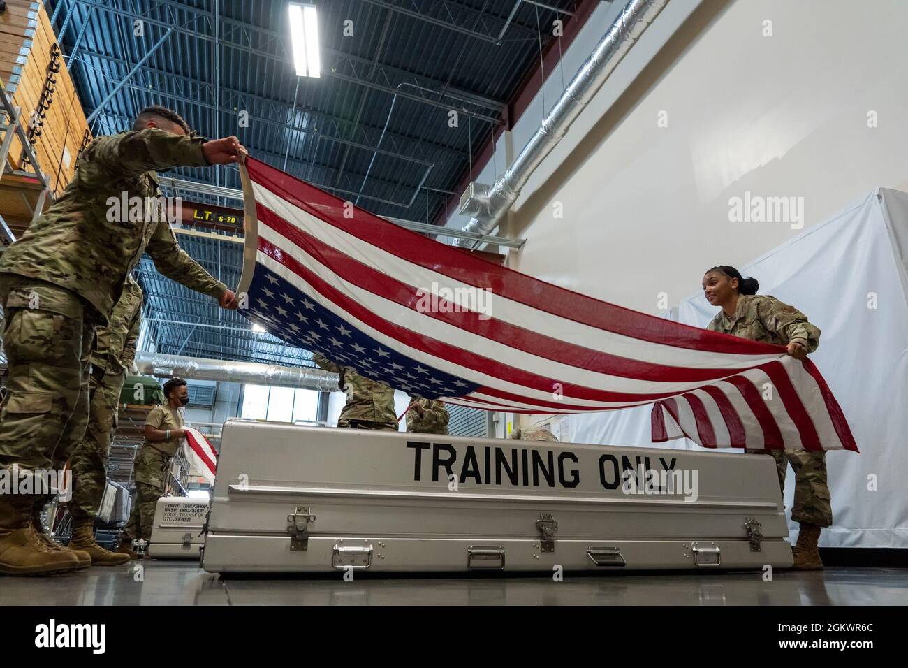 Senior Airmen Adam Ingram, Left, und Deamekiya Hester, Airforce Mortuary Affairs Operations Departures Specialists, üben Flagge, die einen Transfer-Fall auf dem Dover Air Force Base, Delaware, 12. Juli 2021 drapiert. Jeder Transfer-Fall ist auf der Durchreise mit Flaggen drapiert, kann aber einen Ersatz erfordern, um sicherzustellen, dass er für den würdigen Transfer makellos ist. Stockfoto