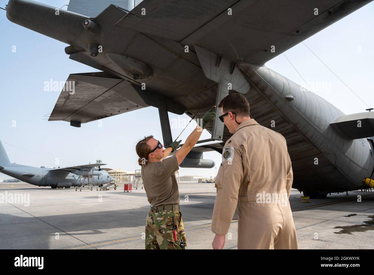 Taylor Drolshagen, die US-Luftwaffe, 41. Expeditionary Electronic Combat Squadron Pilot, zeigt Maj. Joshua Tempel, 380. Expeditionary Operations Support Squadron, wie sie ihre Vorflugkontrollen an einem EC-130H Compass Call-Flugzeug durchführt, bevor sie an einer großen Kraftbeschäftigungsübung auf dem Luftwaffenstützpunkt Al Dhafra, Vereinigte Arabische Emirate, 13. Juli 2021. LFE-Übungen bieten sowohl ADAB als auch anderen CENTCOM- und Koalitionskräften eine einzigartige Gelegenheit, mit internationalen Partnern in fortgeschrittenen Taktiken mit einem breiten Spektrum an Missionssätzen zu trainieren. Stockfoto