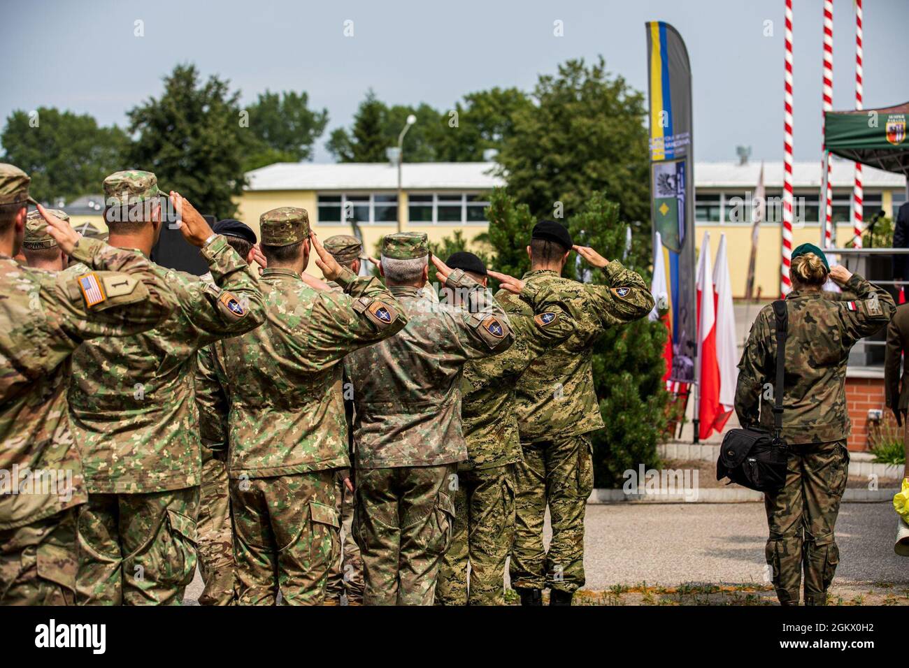 Eine multinationale Gruppe, bestehend aus US-Armee, rumänischen Landstreitkräften und Soldaten der kroatischen Landstreitkräfte, grüßt die polnische Flagge während des 27. Jahrestages der 15. Mechanisierten Brigade in Gizycko, Polen, am 15. Juli 2021. Als eine der Schwestereinheiten der Battle Group Polens innerhalb der multinationalen Division Nord-Osten ermöglicht die 15. Mechanisierte Brigade kollektive Verteidigung und Sicherheit. Stockfoto