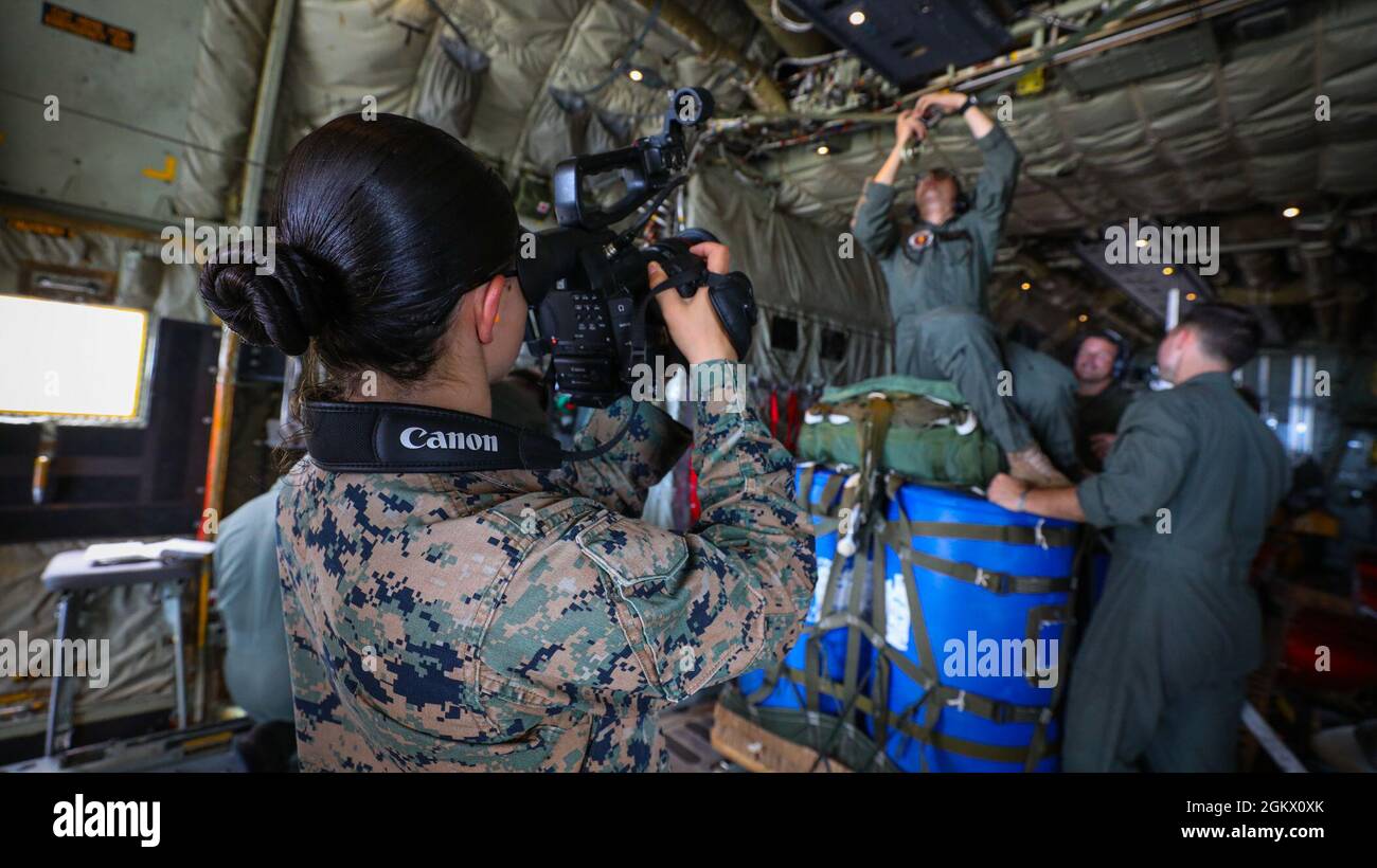 U.S. Marine Corps Lance CPL. Madison Santamaria, ein Kampfvideograf der 3d Marine Logistics Group Communication Strategy and Operations, dokumentiert Marines mit 3d Landing Support Bataillon, Combat Logistics Regiment 3, 3d MLG, die Durchführung von Luftlieferungstrainings mit Marines vom Marine Aerial Refueller Transport Squadron (VMGR) 152 bei IE Shima, Okinawa, Japan, 14. Juli 2021. Die Marineinfanteristen trainierten, um die Kenntnisse und Kenntnisse über Luftlieferungssysteme und Lufteinsätze zu erhalten. 3d MLG mit Sitz in Okinawa, Japan, ist eine nach vorne eingesetzte Kampfeinheit, die als III Marine Expedi dient Stockfoto