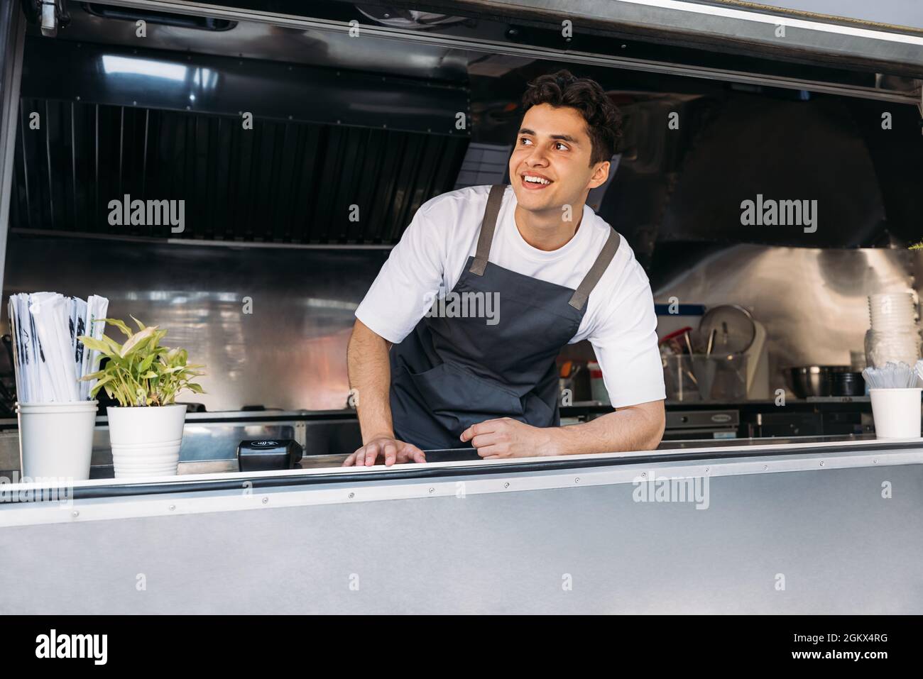 Porträt eines lächelnden Besitzers eines Food-Trucks, der eine Schürze an der Theke trägt Stockfoto