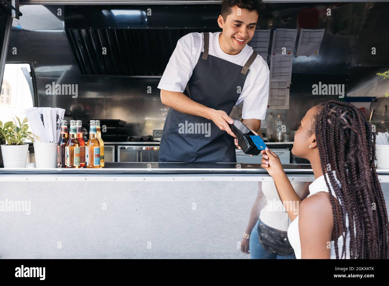Die junge Besitzerin eines Food-Trucks erhält die Zahlung per Kreditkarte von einer Kundin Stockfoto
