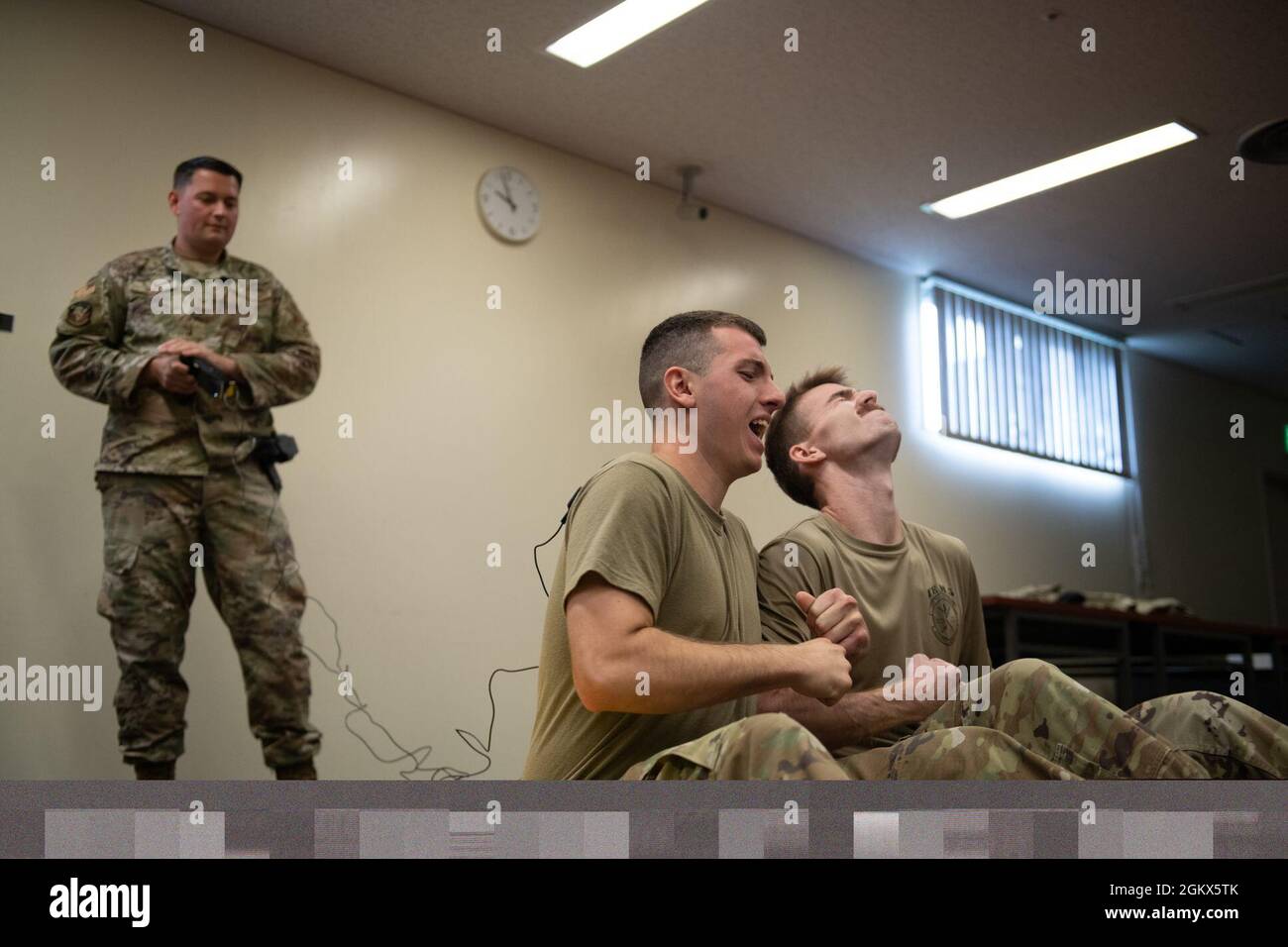 US Air Force Staff Sgt. Matthew Pick, Trainer der 18. Sicherheitskräfte-Geschwader, verwendet einen Taser auf Airman Jordan Vittitow und Airman Michael Sciume II, beide Verteidiger der 18. Sicherheitskräfte-Geschwader, während des Tasertrainings auf der Kadena Air Base, Japan, 15. Juli 2021. Die Exposition gegenüber dem Taser ist für alle Mitglieder der Sicherheitskräfte obligatorisch, um eine Zertifizierung für das Tragen eines Tasers zu erhalten, um vollständig zu verstehen, wie sie den Körper beeinflussen. Stockfoto