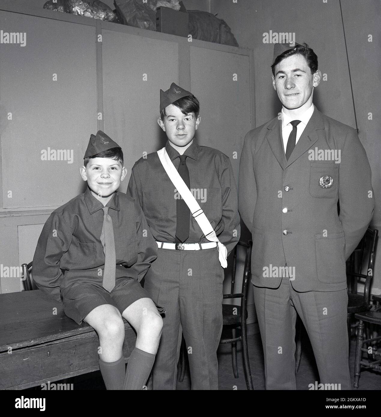 1966, historisch, The Boys Brigade, drei Jungen in BB-Uniformen, Fife, Schottland, Großbritannien. Die Idee einer uniformierten Jugendgruppe, die 1883 von William Alexander Smith in Glasgow, Schottland, als christliche Jugendbewegung gegründet wurde, war damals eine neue Idee. Das Bild hier zeigt drei Jungen unterschiedlichen Alters, die eine neu gestaltete BB-Uniform tragen. Alle drei mit der traditionellen BB-Mütze, aber nur der Junge in der Mitte, der den Gürtel trägt. Zu dieser Zeit organisierte die Brigade die Junior-Sektion, die früher als die Life Boys bekannt war, Um Ein neues Junior-Sektion-Leistungskonzept einzuführen. Stockfoto