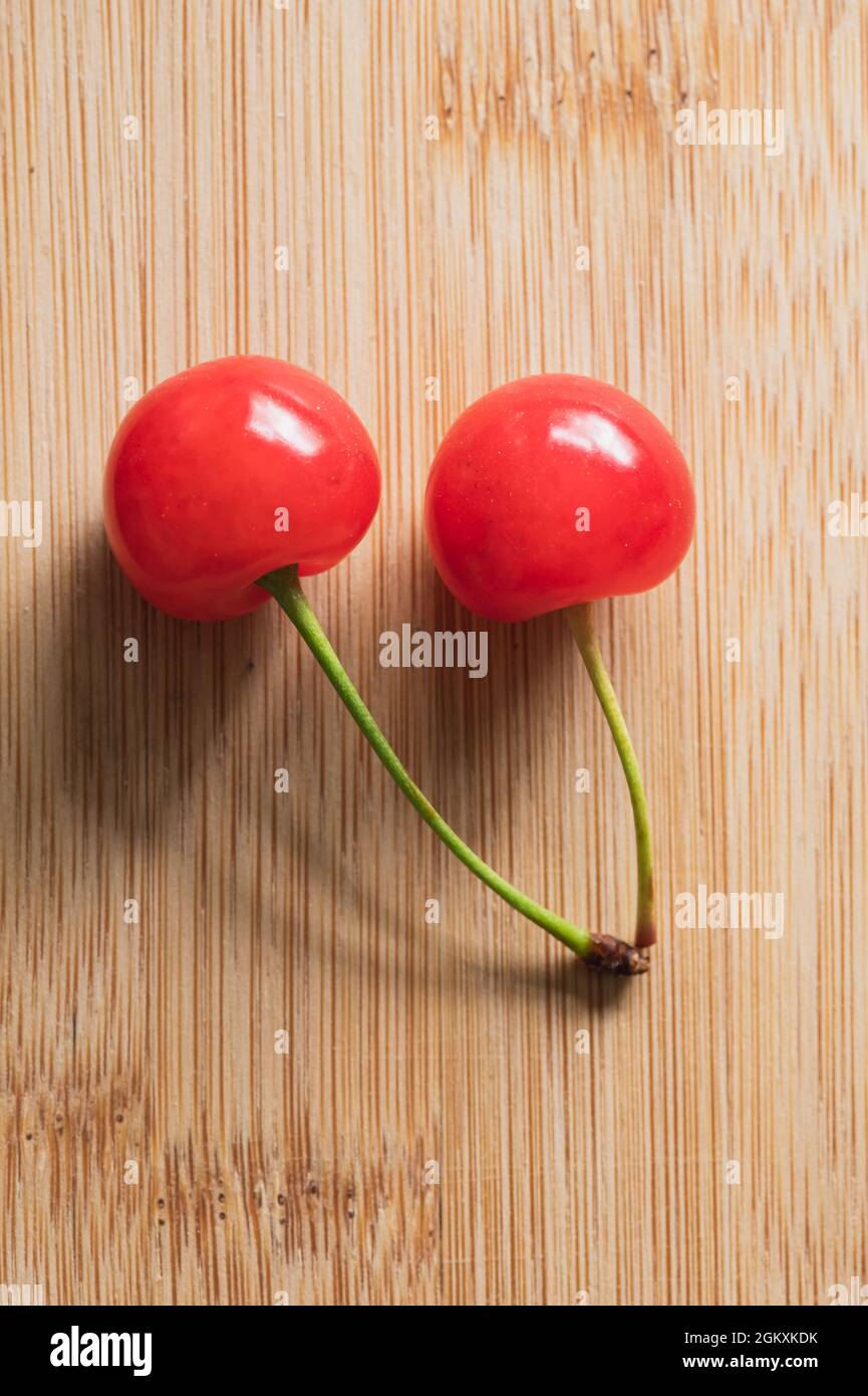Zwei rote Kirschen mit Stielen auf Holzhintergrund Stockfoto