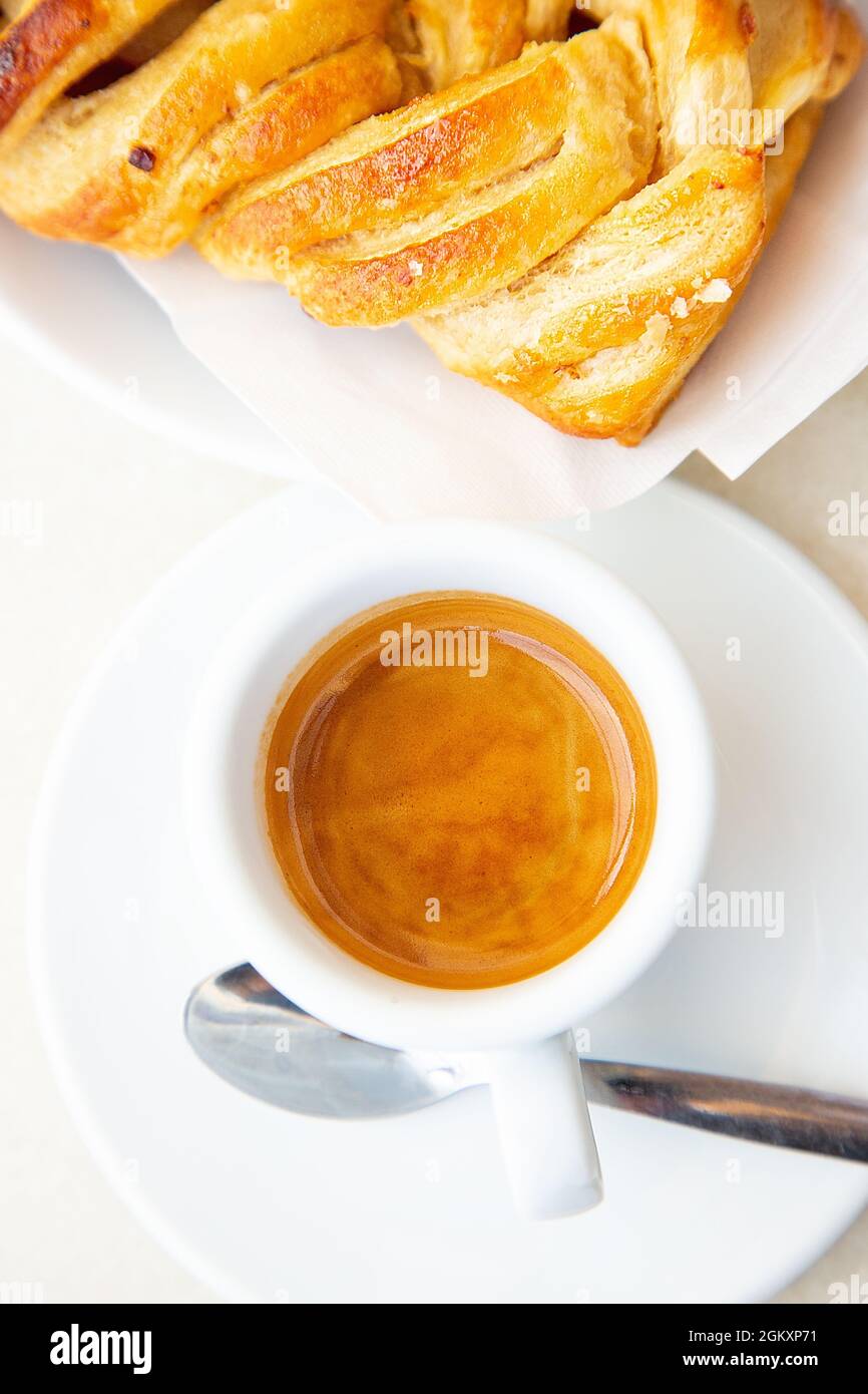 Blick von oben auf weiße Tasse Kaffee Ristretto und Croissant. Traditionelles italienisches Frühstück. Konzept „Guten Morgen“. Tageslicht. Hausgemachte Bäckerei. Ginseng heiß Stockfoto