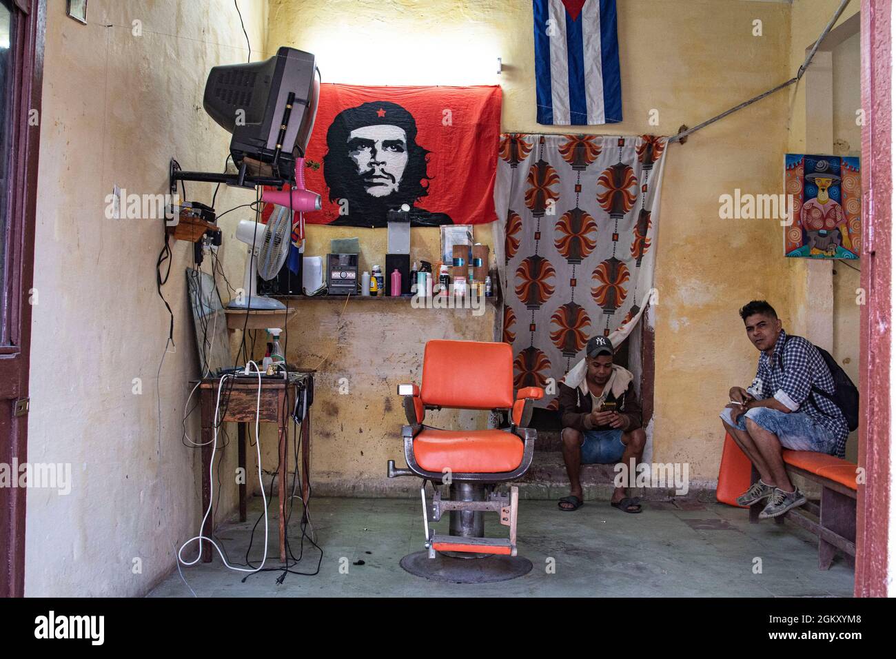 Ein Barbier und ein Kunde sitzen in einem Friseurladen und warten darauf, dass Leute für einen Haarschnitt kommen. Stockfoto