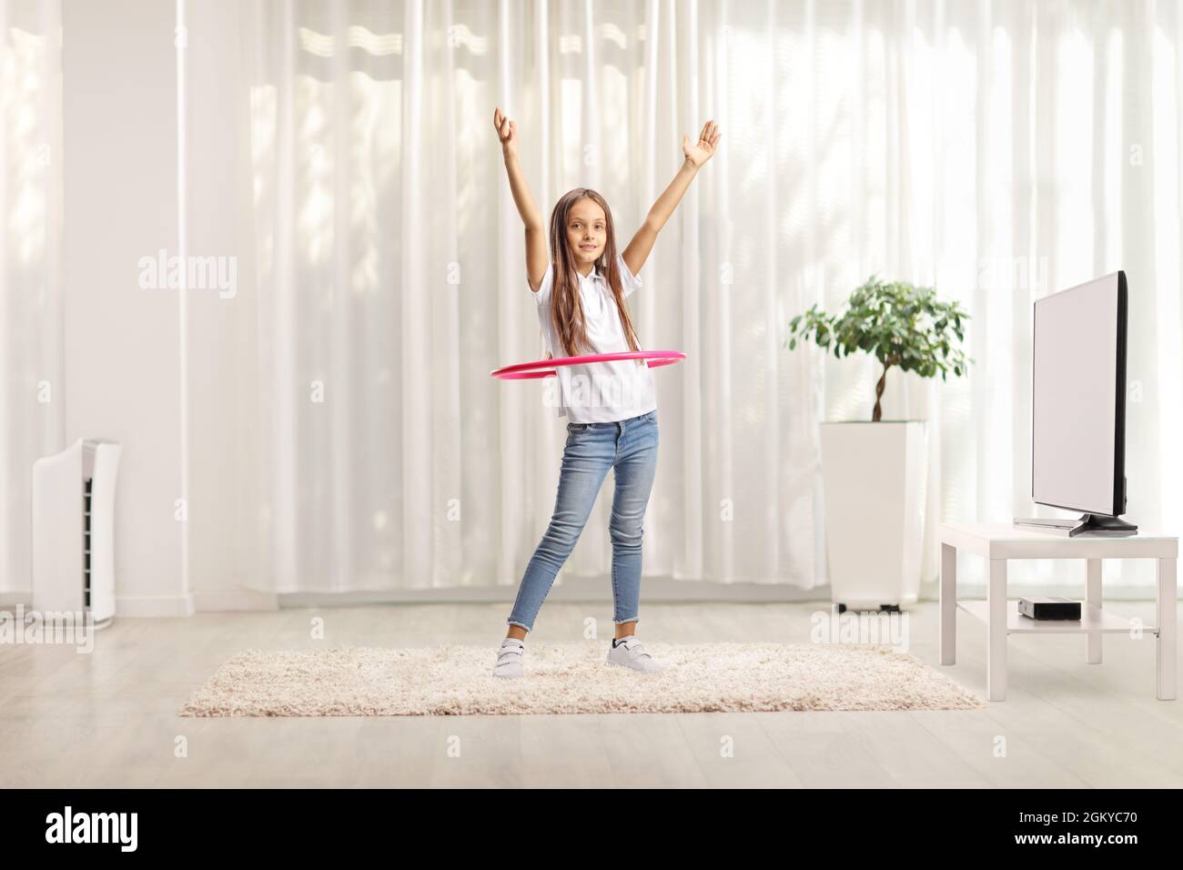 Kind dreht einen Hula Hoop Reifen zu Hause in einem Wohnzimmer Stockfoto