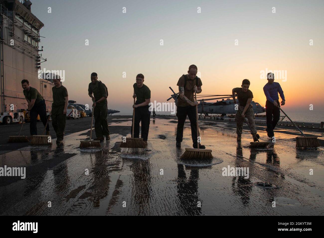 210731-N-LN075-2004 ARABIAN GULF (31. Juli 2021) Seeleute, die dem amphibischen Sturmschiff USS Iwo Jima (LHD 7) der Wasp-Klasse zugewiesen wurden, scheuern das Flugdeck des Schiffes, 31. Juli. Iwo Jima wird im Einsatzgebiet der 5. US-Flotte eingesetzt, um Marinestützpunkte zu unterstützen, um die maritime Stabilität und Sicherheit in der Zentralregion zu gewährleisten und das Mittelmeer und den Pazifik durch den westlichen Indischen Ozean und drei strategische Engpässe zu verbinden. Stockfoto