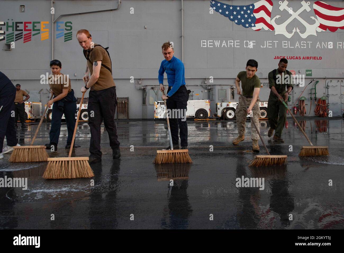 210731-N-LN075-2012 ARABIAN GULF (31. Juli 2021) Seeleute, die dem amphibischen Sturmschiff USS Iwo Jima (LHD 7) der Wasp-Klasse zugewiesen wurden, scheuern das Flugdeck des Schiffes, 31. Juli. Iwo Jima wird im Einsatzgebiet der 5. US-Flotte eingesetzt, um Marinestützpunkte zu unterstützen, um die maritime Stabilität und Sicherheit in der Zentralregion zu gewährleisten und das Mittelmeer und den Pazifik durch den westlichen Indischen Ozean und drei strategische Engpässe zu verbinden. Stockfoto