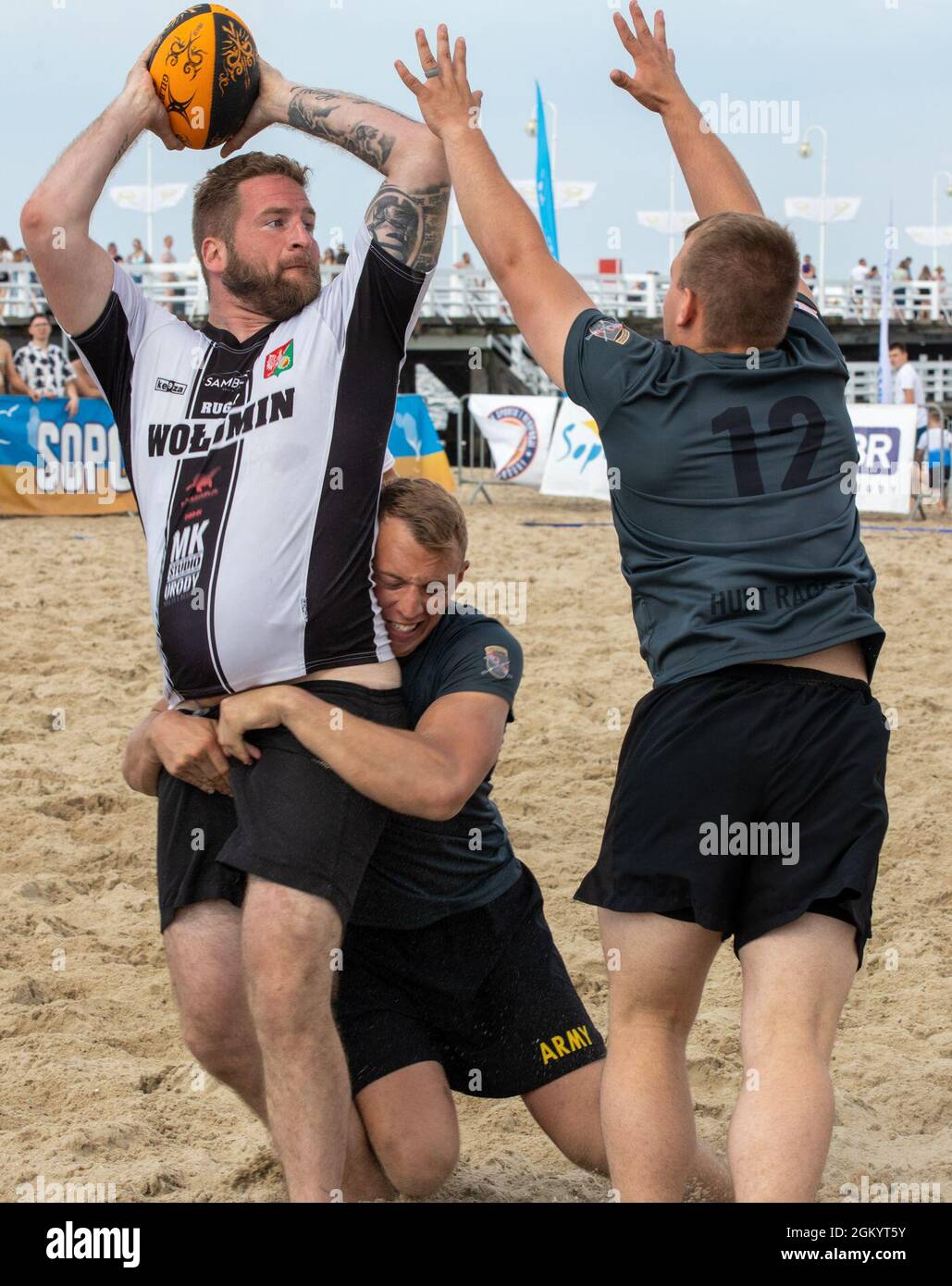 Sgt. Derek Dow, Teamleiter der Headquarters and Headquarters Company, 3. Bataillon „Dark Rifles“, 161. Infanterie-Regiment, greift einen Gegner von hinten als PFC an. Cody Hengeveld blockiert den Pass beim Sopot International Beach Rugby Turnier in Sopot, Polen, 31. Juli 2021. Die Soldaten nahmen an dem Turnier Teil, um die Bande mit den polnischen Einheimischen zu stärken und die Interoperabilität von ‘Dark Rifles’ zu erhöhen. Stockfoto