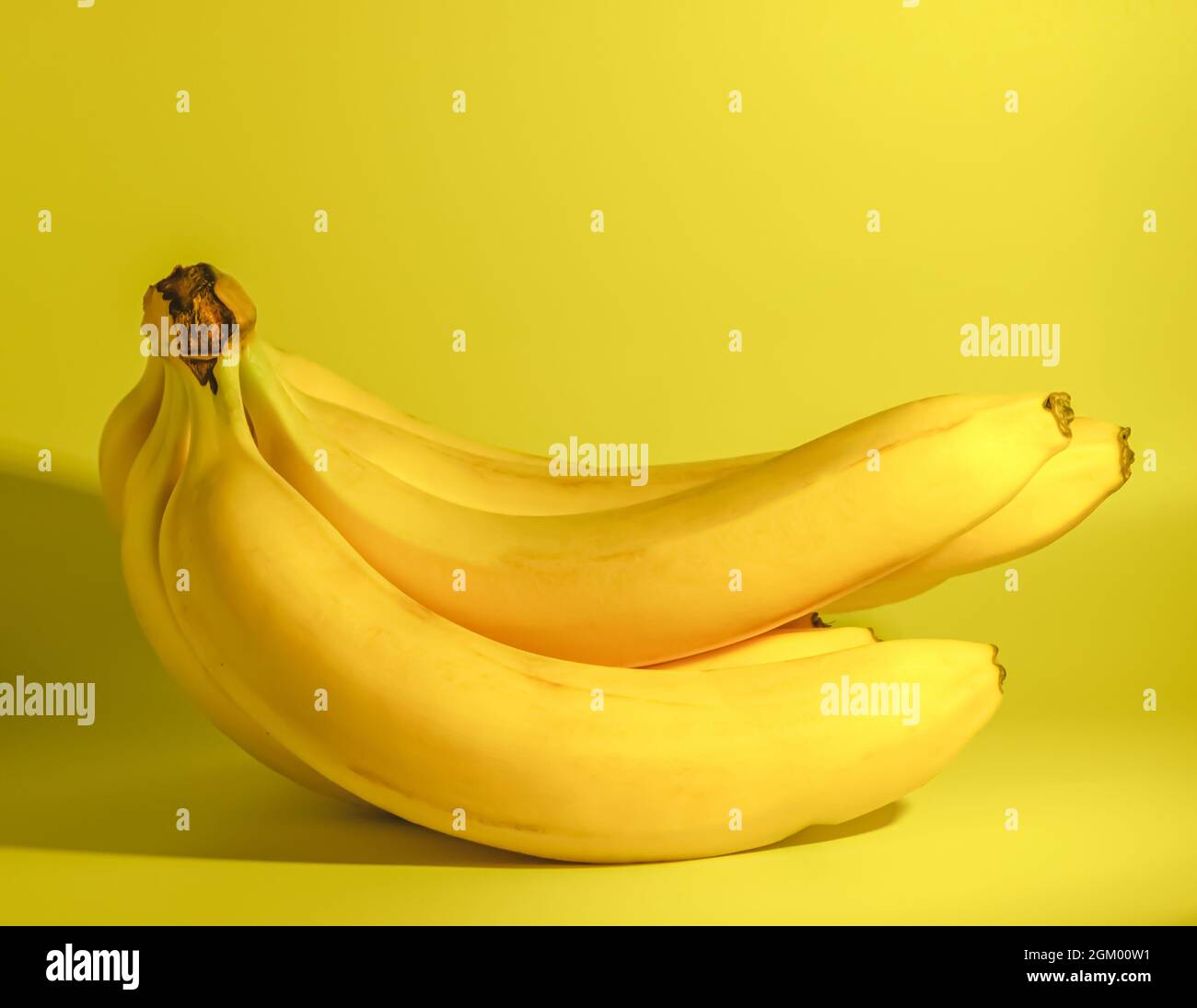 Ein Haufen frischer reifer Bananen liegt auf einem gelben Hintergrund. Horizontales Foto. Stockfoto