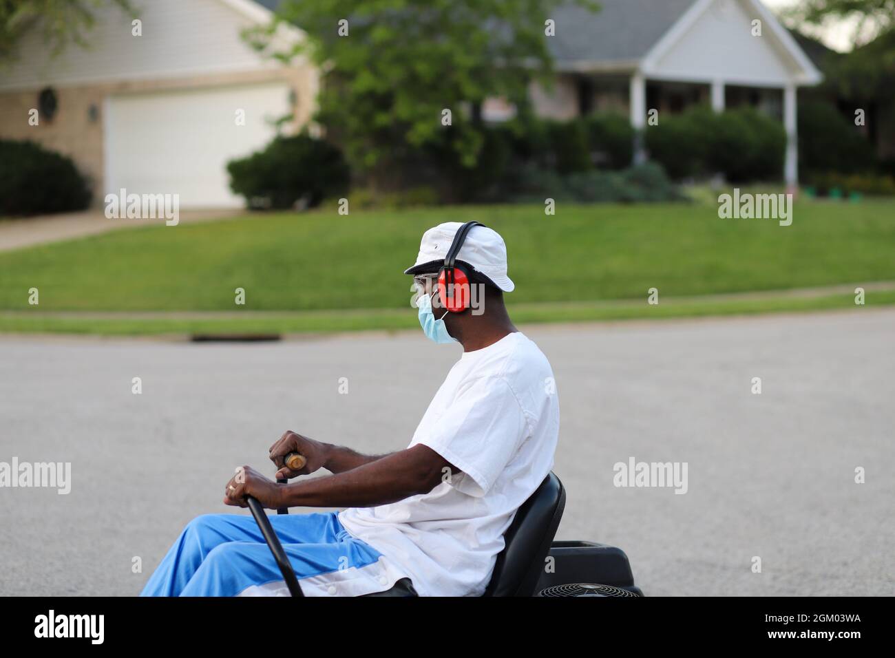 Ein schwarzer afroamerikanischer Mann, der auf einem Rasenmäher reitet Stockfoto