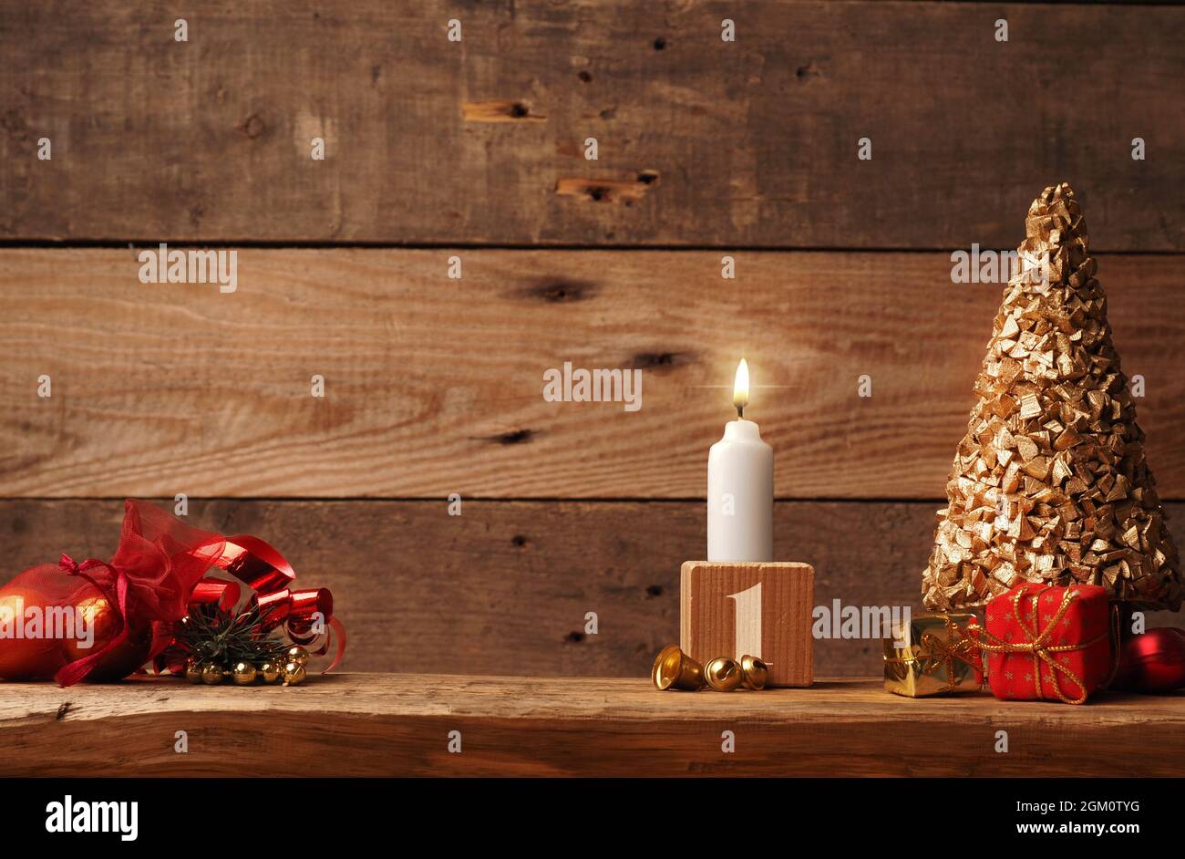 Erster Advent, eine Kerze brennt auf einem rustikalen Holztisch mit Weihnachtsdekoration Stockfoto