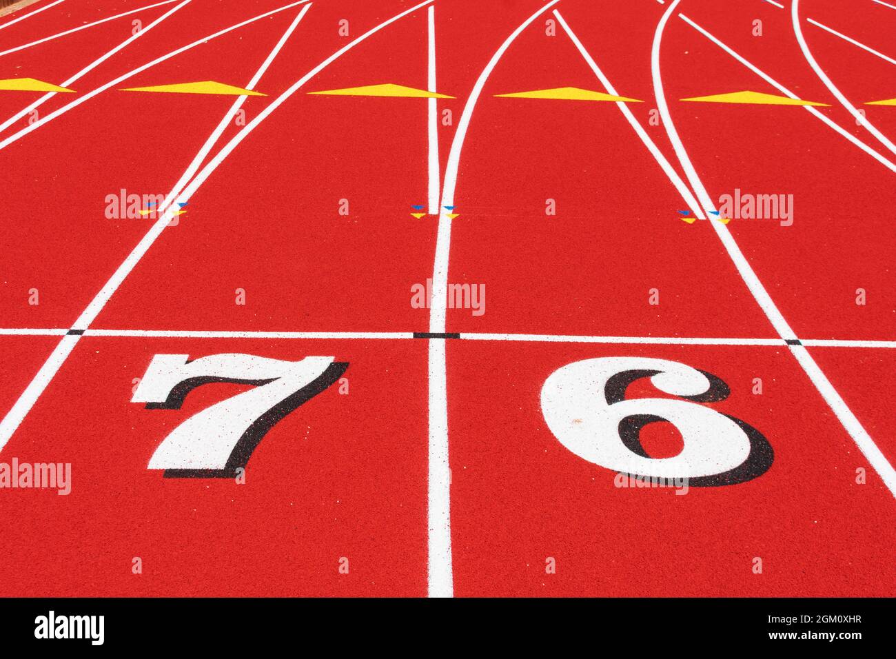 Track and Field Race Course Startlinie mit den Nummern 7 und 6 auf der Allwetter-Tartan-Gummilaufstrecke. Stockfoto