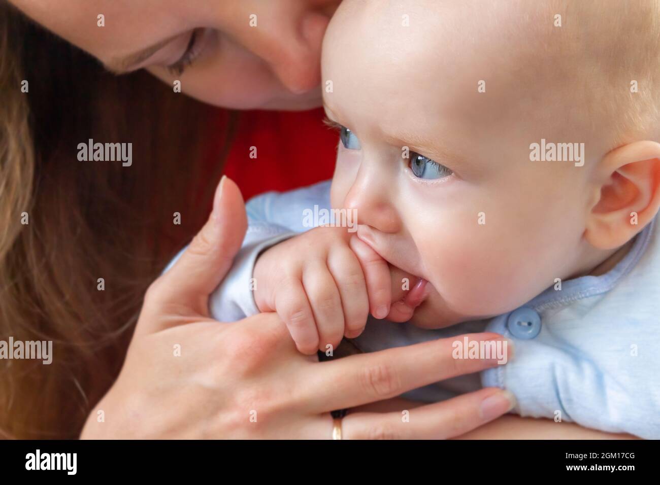 Kleines Baby, das den Finger der Mutter im Mund hält. Stockfoto