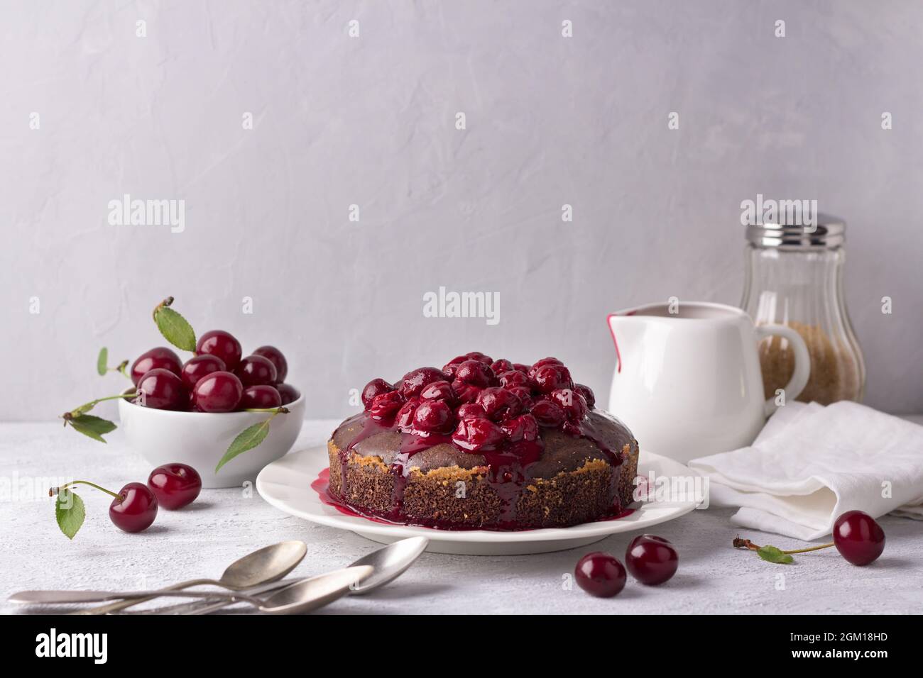 Köstliche hausgemachte Schokoladenkuchen mit Kirschsauce, mit frischer Kirsche auf grauem Hintergrund Stockfoto