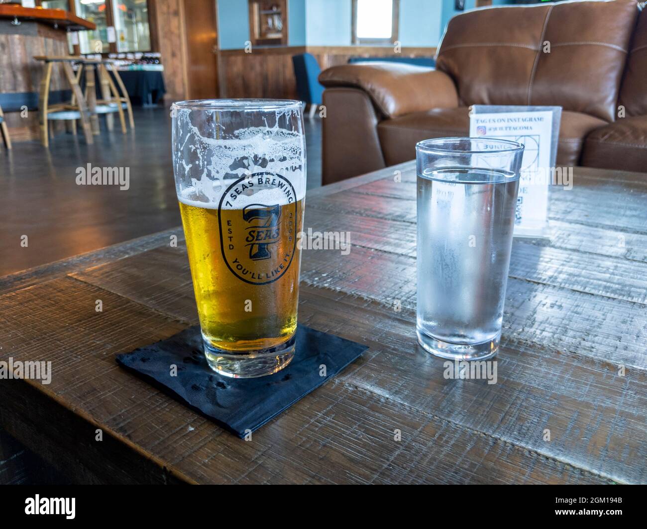 Tacoma, WA USA - ca. August 2021: Blick auf ein schaumiges Pilsner-Bier auf einem rustikalen Tisch in der 7 Seas Brewery. Stockfoto