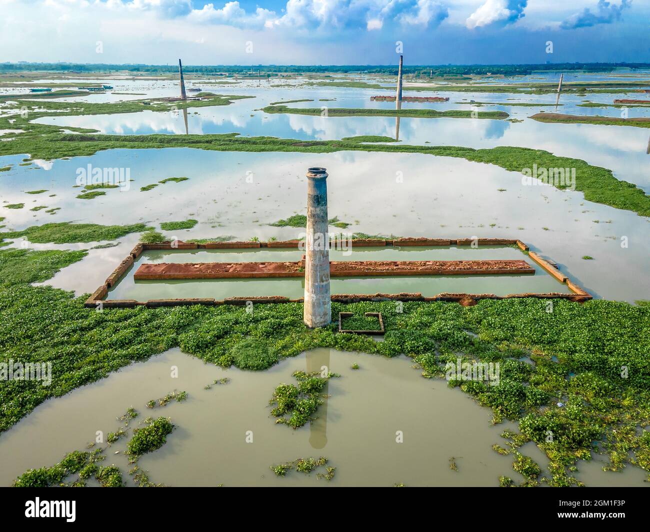 DHAKA, BANGLADESCH - 16. SEPTEMBER 2021: Luftaufnahme eines Schornsteins aus der lokalen Ziegelfabrik, die von Monsunregen in der Nähe von Savar, Dhaka, Bangladesch überschwemmt wurde. Hunderte von Ziegelfabriken scheinen nach schweren Überschwemmungen fast unter Wasser verschwunden zu sein. Die Gebäude waren während der gesamten Monsunsaison durch heftige Regenfälle mit Wasser bedeckt. Die Arbeiter konnten Tausende von Ziegelsteinen retten, aber viele gingen durch das 20 Meter tiefe Hochwasser verloren. Am 16. September 2021 in Dhaka, Bangladesch. (Foto von Mustasinur Rahman Alvi/ Eyepix Group) Stockfoto