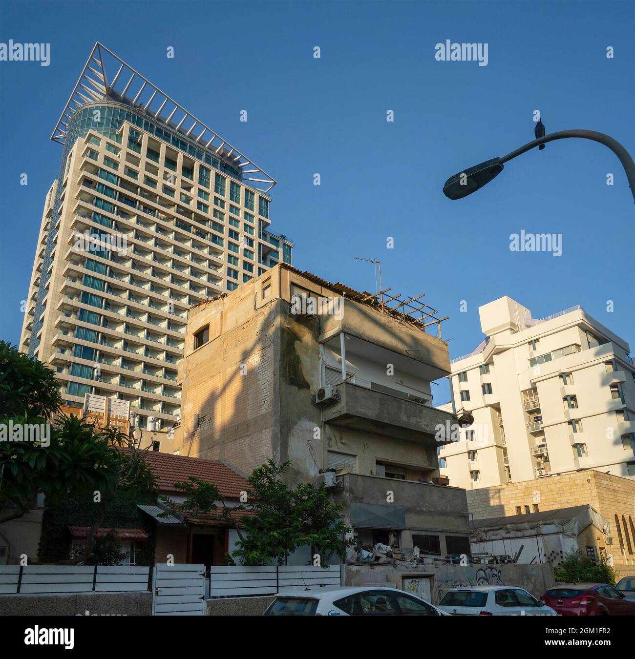 Tel Aviv, Israel - 20. August 2021: Ein altes, vernachlässigtes Gebäude inmitten moderner Gebäude in einer Tel Aviv-Straße. Stockfoto