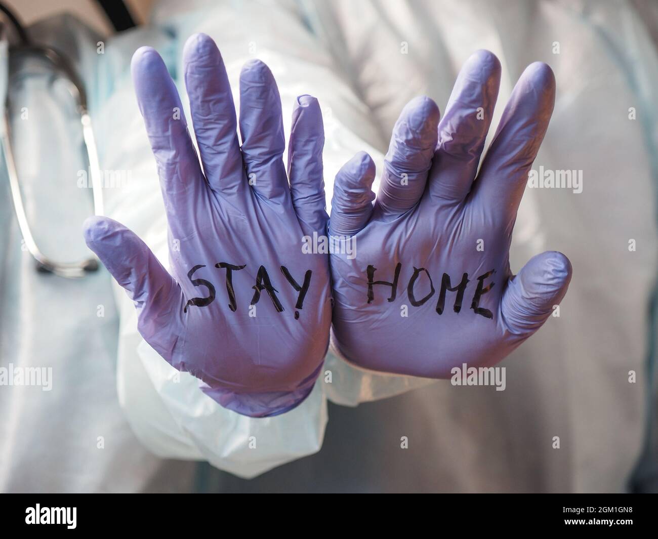 Zwei Ärzte halten ihre Hände aus und sagen den Leuten, dass sie bleiben sollen Zu Hause Stockfoto