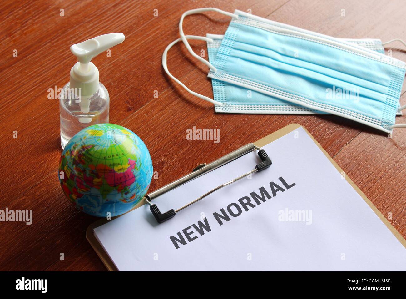 Medizin- und Gesundheitskonzept. Gesichtsmask, Händedesinfektionsmittel, Erdkugel und Papierzwischenablage mit Text NEW NORMAL Stockfoto