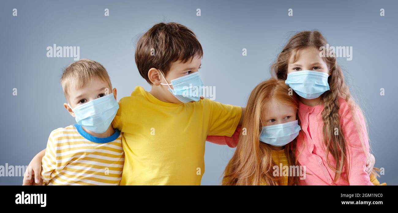 Gruppe von vier Kindern in medizinischer Maske im Innenbereich. Stockfoto