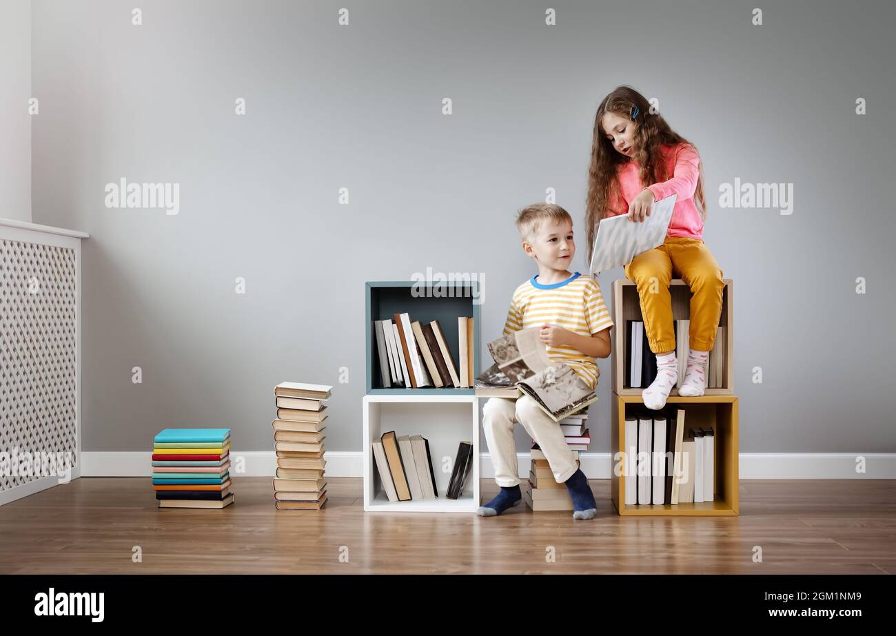 Zwei Kinder sitzen im Zimmer und lesen Bücher Stockfoto