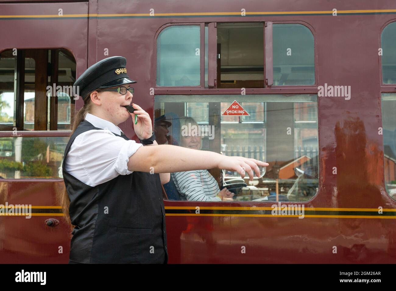 Kidderminster, Worcs, Großbritannien. September 2021. Kaylie Armishaw, eine freiwillige Dampfeisenbahn-Dispatchin, pfeift, als am Eröffnungstag der Herbst-Dampfgala der Severn Valley Railway, Kidderminster, Worcestershire, ein Dampfzug auf eine Tagesreise einbricht. Die Gala dauert bis Sonntag, den 19. September und bietet Gastloks. Kredit: Peter Lopeman/Alamy Live Nachrichten Stockfoto