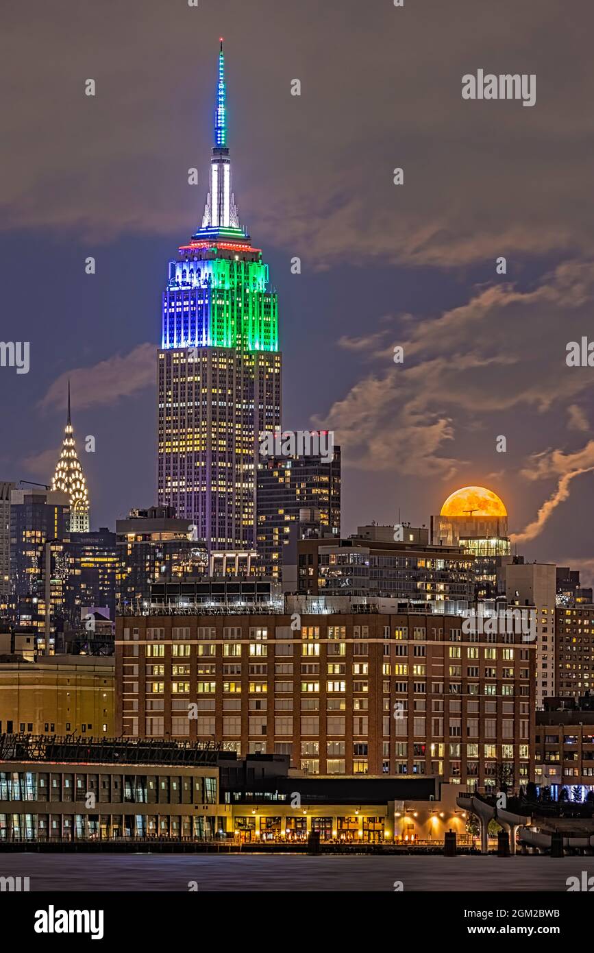 NYC Skyline Blue Moon - der blaue Mond steigt neben zwei beleuchteten Wahrzeichen auf, dem Empire State Building ESB und dem Chrysler Building in der Mitte Stockfoto
