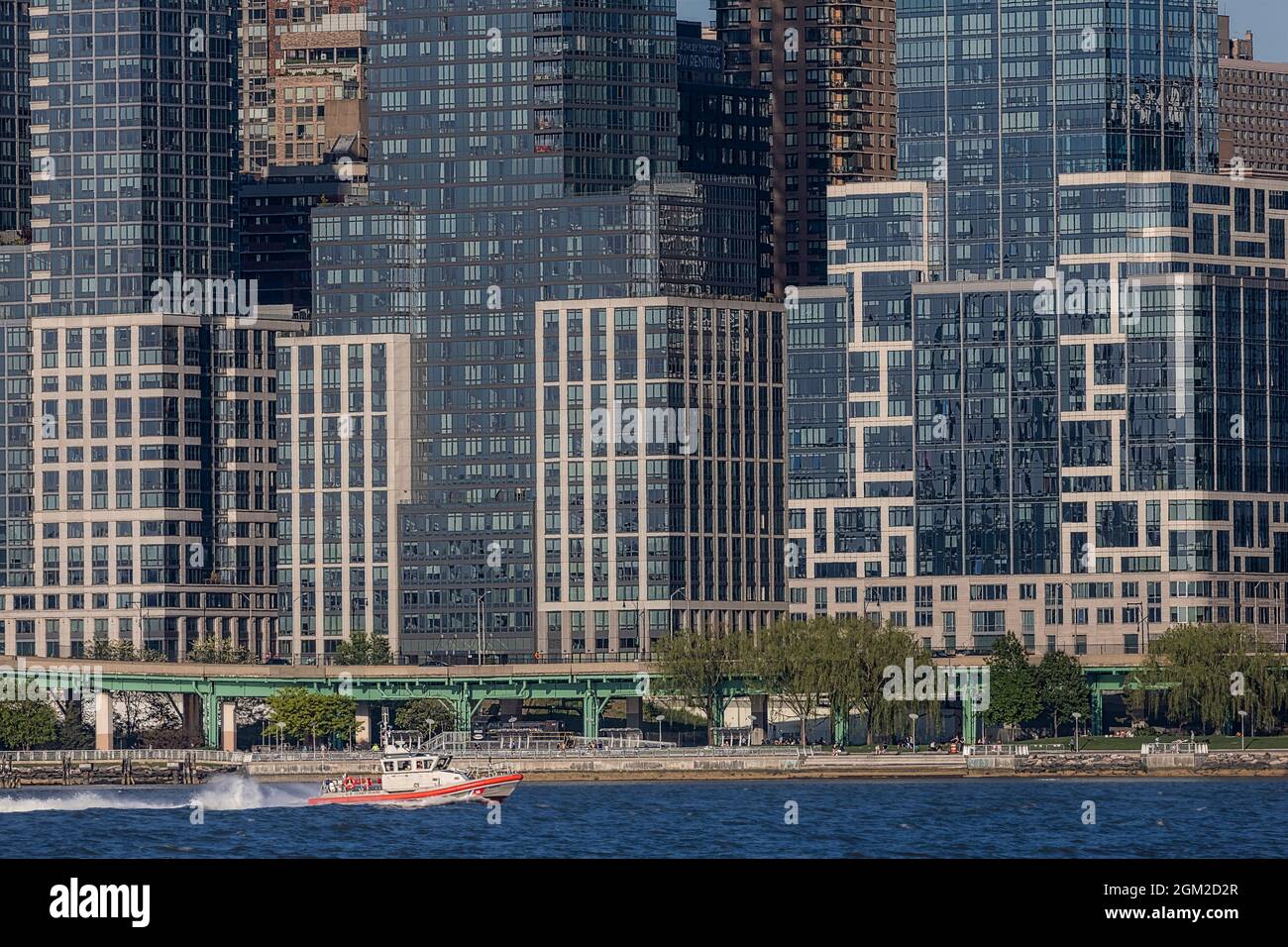 US Coast Guard NYC - Ein Boot der US Coast Guard fährt an der Skyline von New York City in Upper Manhattan vorbei. Im Hintergrund sind einige der zu sehen Stockfoto