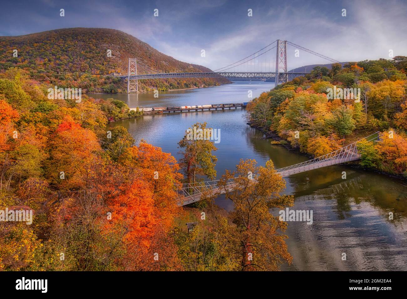 Fall an der Bear Mountain Bridge - Blick nach Süden auf die Bear Mountain Bridge, CSX-Zug auf der Brücke über den Hudson River und Popolopen-Fußgängerbrücke d Stockfoto