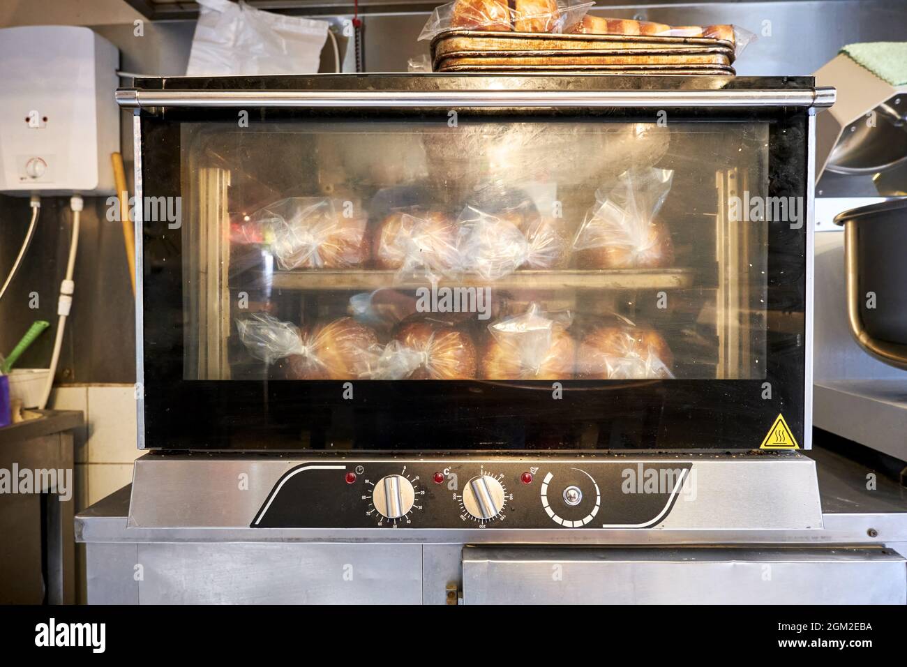 Industrieller kleiner Brotbackofen mit gekochtem Brot in einer Backküche im Restaurant. Stockfoto